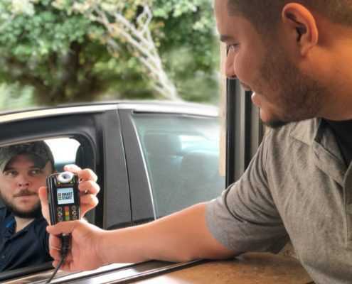 Smart Start Technician hands Ignition Interlock Device customer in car