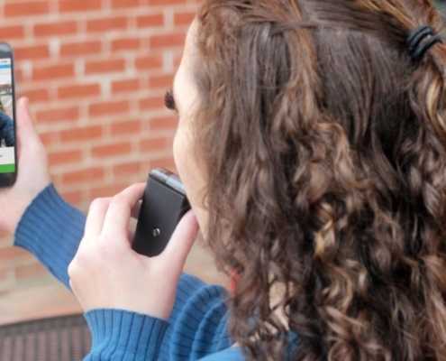 Woman blowing into BreathCheck portable alcohol monitoring device