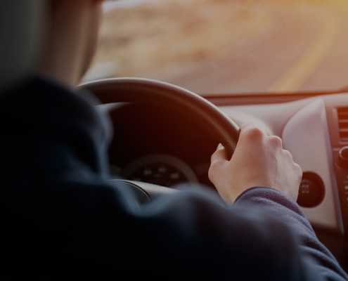 behind a man in a car with his hands on the wheel